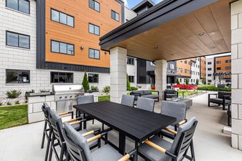 a patio with a table and chairs and a grill